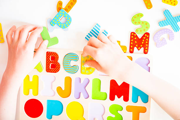 istock Education, child's hands sorting colorful letters in alphabet puzzle 475433118