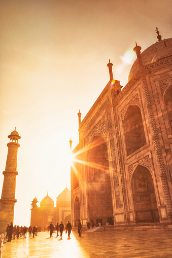 Sun peeks around the Taj Mahal as tourists wander the complex in Agra, India.