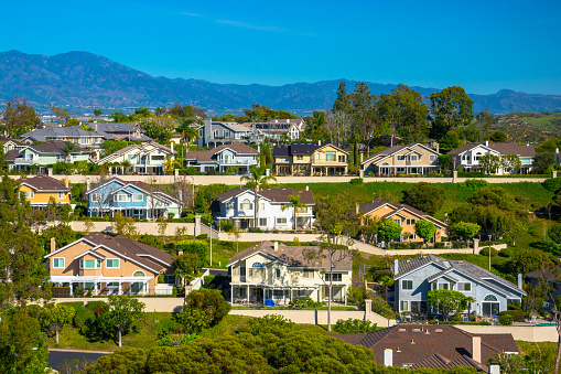 A hillside with many houses in Irvine in southern Orange County, California, with mountains in the background.