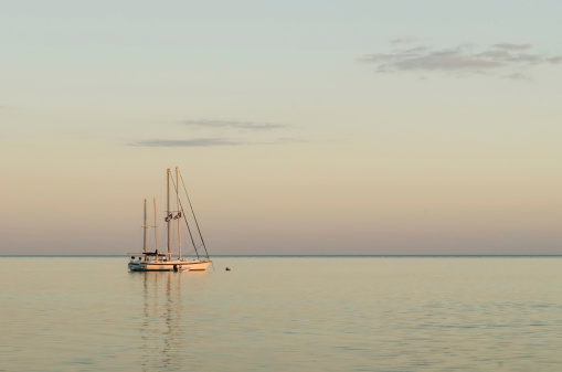 Two sailboats flying the Jolly Roger anchored offshore at sunset on a calm evening in the Florida Keys