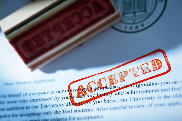 University Application Acceptance Notification Letter with ACCEPTED Stamp An acceptance letter from a university application. An university application form and the letter of acceptance with a red rubber stamp of "Accepted" on a table top still life. Photographed close-up in horizontal format with selected focus on the rubber stamp impression. college acceptance letter stock pictures, royalty-free photos & images
