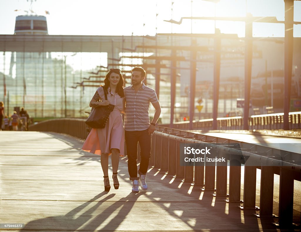 Outdoor portrait of young couple in the city at sunset Full lenght portrait of contemporary happy young couple embracing and walking in the city at sunset. 2015 Stock Photo