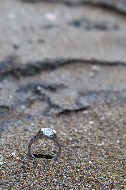 istock Wedding ring as symbol laying on the beach sand 475446310