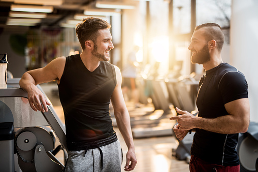 Young men taking a break from exercising in a gym and communicating.