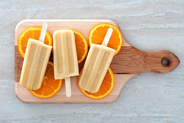 istock Orange yogurt popsicles on a wooden paddle board 475448096