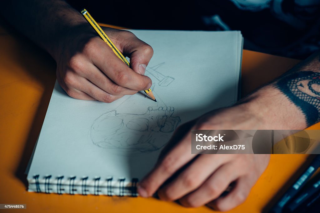 Tattoo Artist Drawing Young tattoo artist draw a new sketch on paper before tattooing on skin 20-24 Years Stock Photo