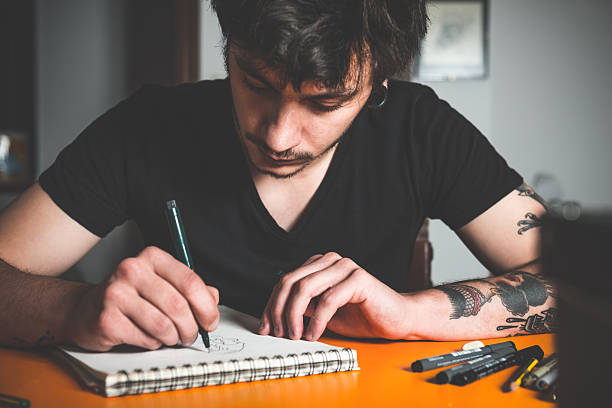 Young male artist sits on the floor of his messy living room, absorbed in drawing sketches with pencil, surrounded by scattered supplies and inspiration.