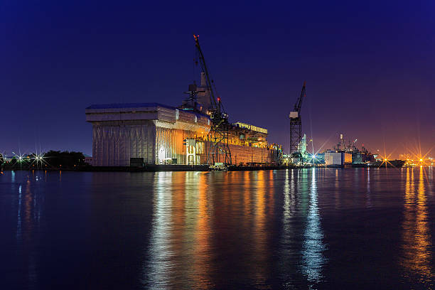 Repair of ship at the Portsmouth/Norfolk bay area shipyard at night showing the reflections on the water.   