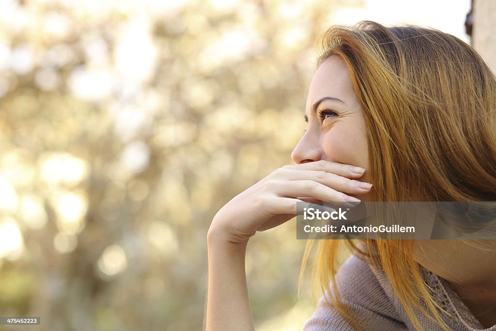 Happy woman laughing covering her mouth with a hand Happy woman laughing covering her mouth with a hand with a warmth background Covering Stock Photo