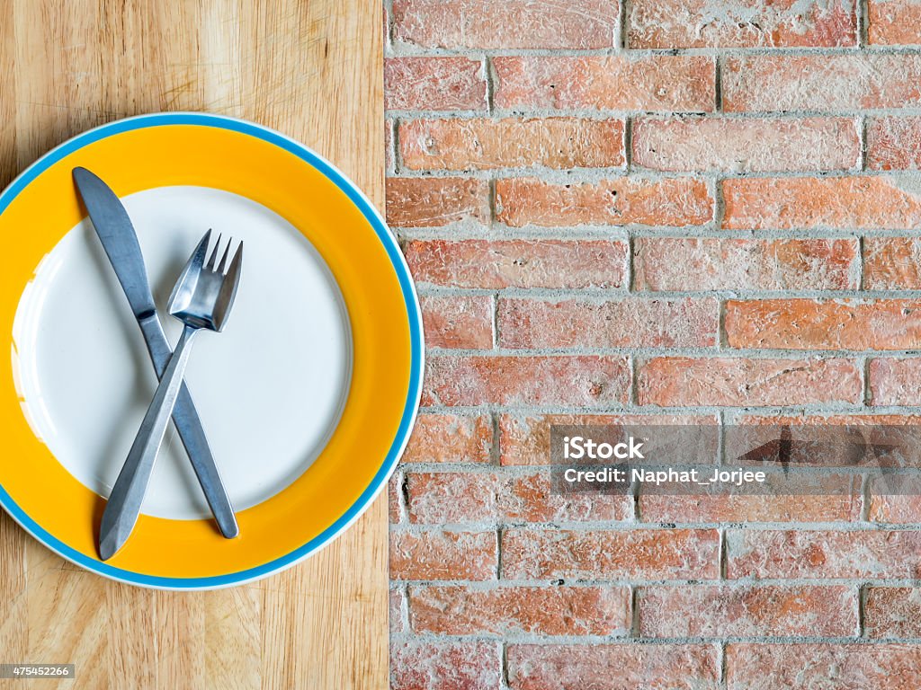Blank plate on wooden top/ rustic brick copy space background Top view of blank plate on wooden top/ rustic brick copy space background 2015 Stock Photo