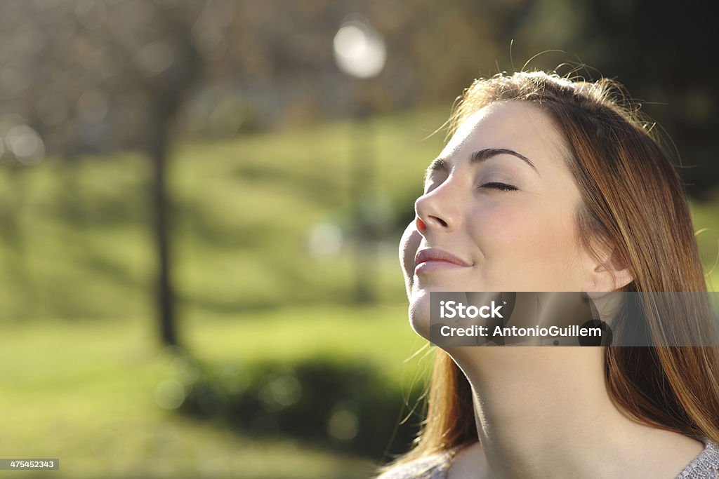 Portrait of a relaxed woman breathing deep in a park Portrait of a relaxed woman breathing deep in a park with a warmth background and backlit Breathing Exercise Stock Photo