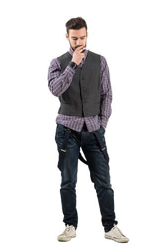 Young hipster smoking cigarette looking down. Full body length portrait isolated over white background.