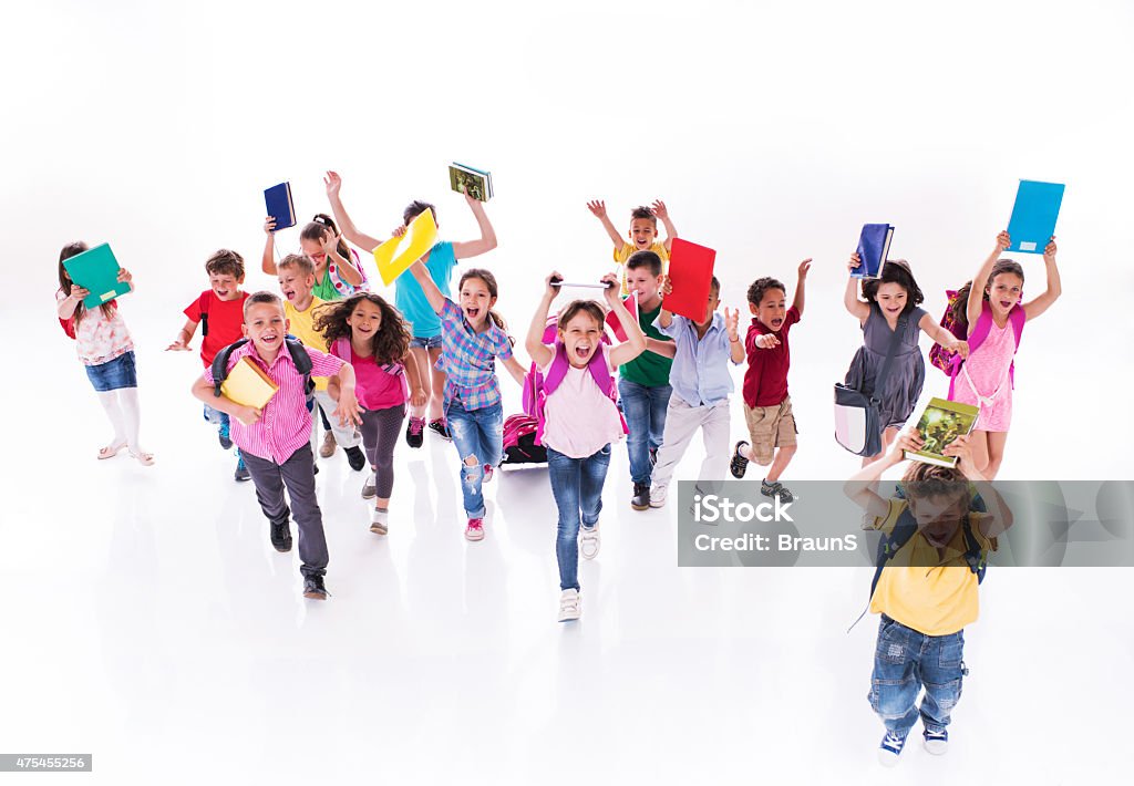 Crowd of cheerful elementary students running with books. Large group of cheerful school children running together with books and having fun. Running Stock Photo