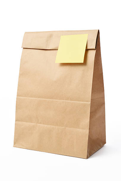 istock Brown paper bag with yellow sticky note on white background 475455590