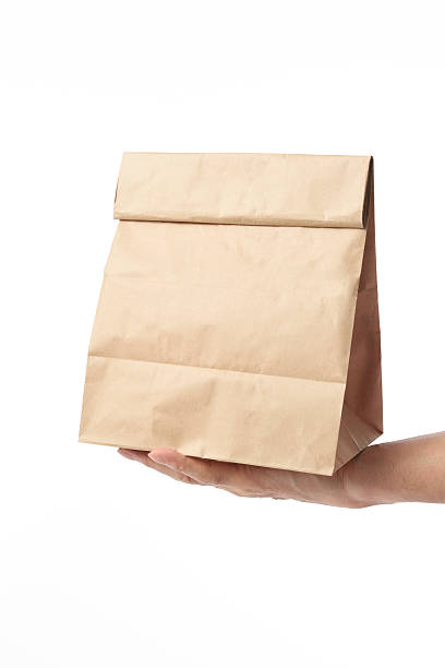 istock Holding a blank brown paper bag on white background 475455596