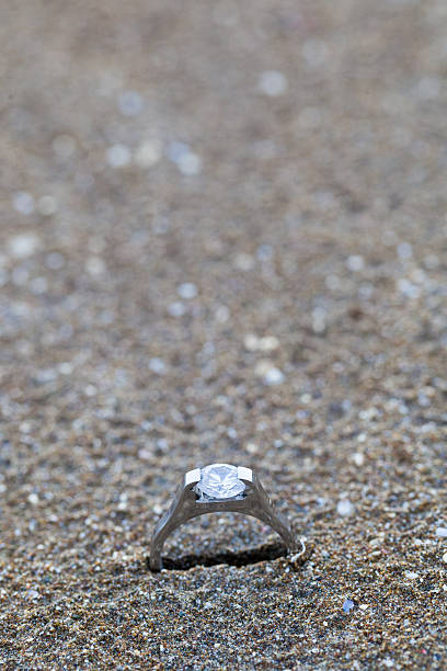 istock Wedding ring as symbol laying on the beach sand 475457582