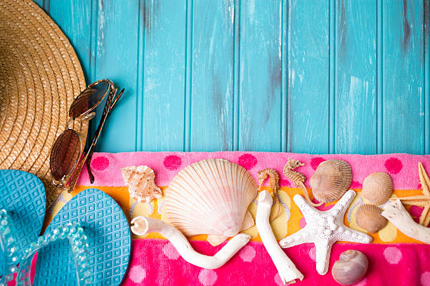 Summer vacation scene. Seashells, sandals on beach towel. Blue background.