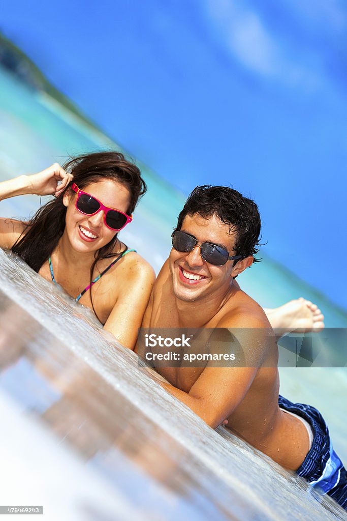 Happy young attractive hiapanic couple on a turquoise tropical beach Happy young attractive hispanic couple lying and talking on a turquoise tropical beach Adolescence Stock Photo