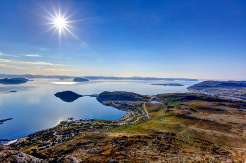 Hammerfest and Rypefjord on a clear summer day. The sun is shining from a blue sky. The picture is taken from the mountaintop called \