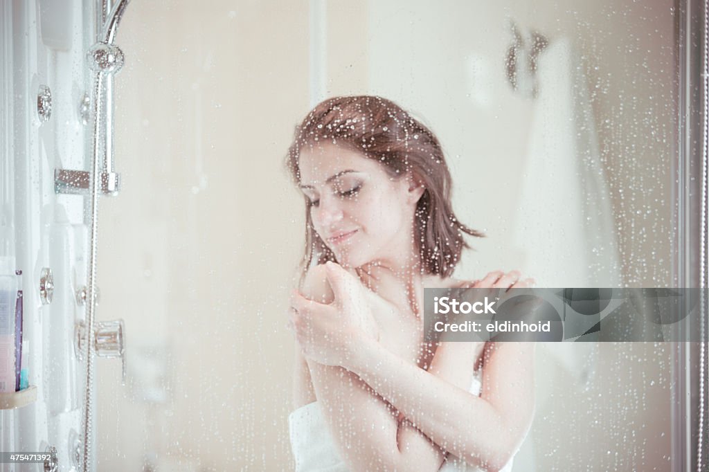 Beautiful brunette woman taking shower after long stressful day Beautiful brunette woman taking shower after long stressful day.Woman showering and enjoying bath.Using douche shower gel,body lotion,shower relaxing muscles.Depilation and anti cellulite treatment. Shower Stock Photo