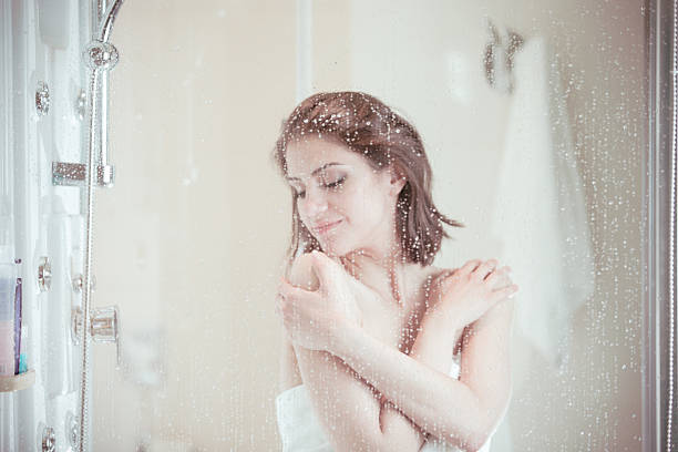 Beautiful brunette woman taking shower after long stressful day stock photo