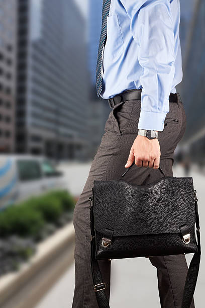 homme d'affaires marchant et en tenant une mallette en cuir dans son han - book holding necktie businessman photos et images de collection