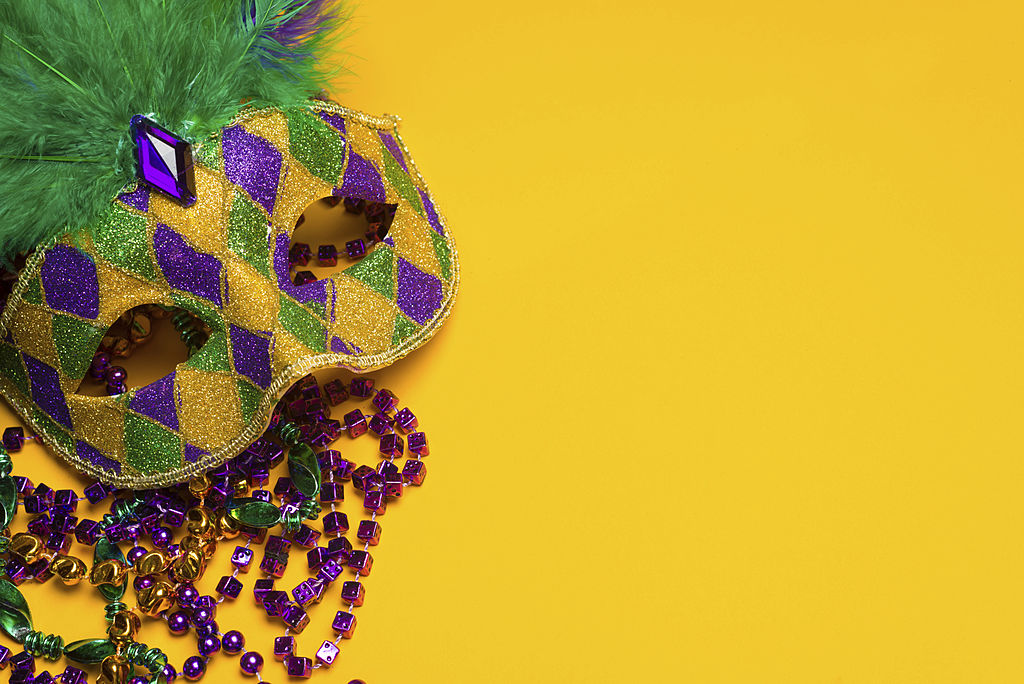 A festive, colorful mardi gras or carnivale mask on a yellow background.  Venetian mask.