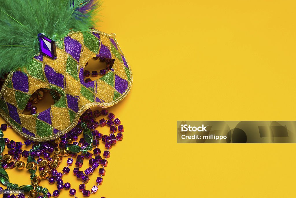 Colorful Mardi Gras or venetian mask on a yellow A festive, colorful mardi gras or carnivale mask on a yellow background.  Venetian mask. Mardi Gras Stock Photo
