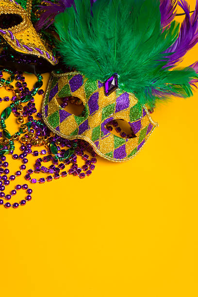 Colorful group of Mardi Gras or venetian masks on yellow A festive, colorful group of mardi gras or carnivale masks on a yellow background. Venetian masks. purple and gold masquerade masks stock pictures, royalty-free photos & images