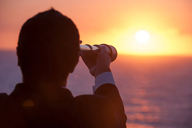 istock Businessman looking to the future with telescope at sunrise. 475485590