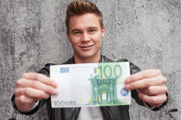Casual young guy holding 100 euro note stock photo