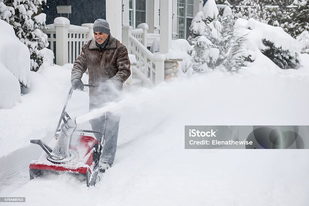 Man clearing driveway with snowblower Man using snowblower to clear deep snow on driveway near residential house after heavy snowfall. Snowblower Stock Photo