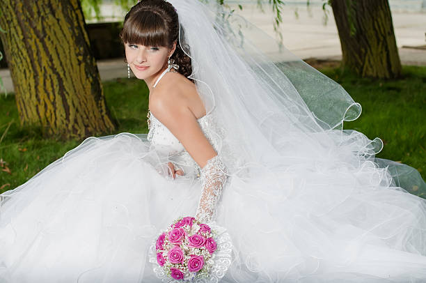 istock Young beautiful bride in wedding dress with a bouquet 475489521