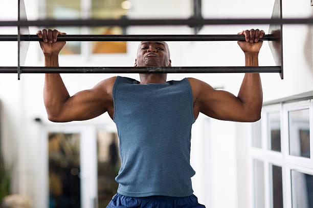 hombre africano haciendo pull-ups en un bar - moviendo hacia abajo fotografías e imágenes de stock