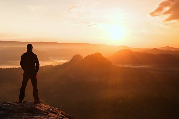 istock Hiker stand on sharp rock empire above foggy morning valley 475493232