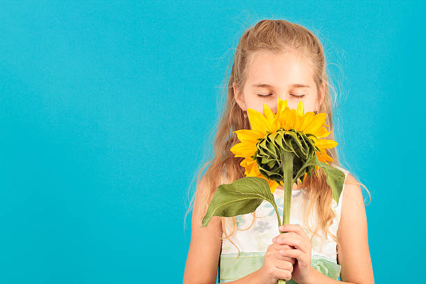 istock Girl with closed eyes smelling a sunflower 475493976