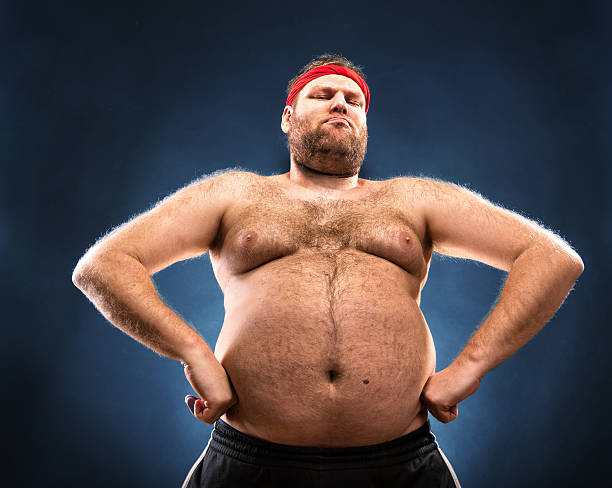 Fat man imitating muscular build Fat man imitating muscular build. Low angle view fat guy no shirt stock pictures, royalty-free photos & images