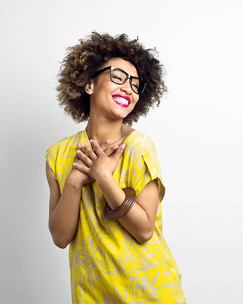 Portrait of excited afro american woman wearing yellow top and nerd glasses. Studio shot, white background. 