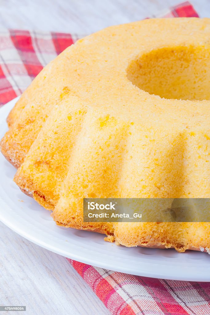 Round-shaped tasty lemon cake Round-shaped tasty lemon cake on white plate on wooden table 2015 Stock Photo