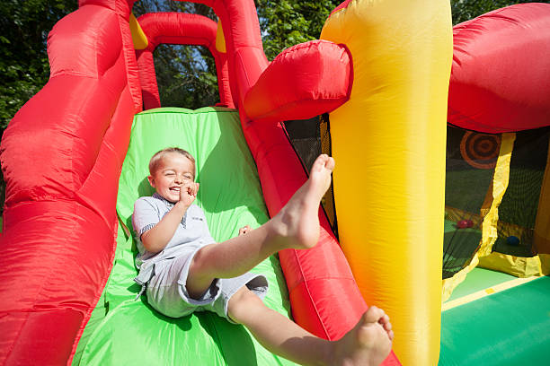 niño en tobogán inflable castillo inflable para saltar - inflatable child playground leisure games fotografías e imágenes de stock