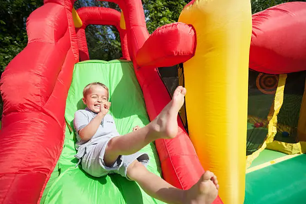 Small boy jumping down the slide on an inflatable bouncy castle