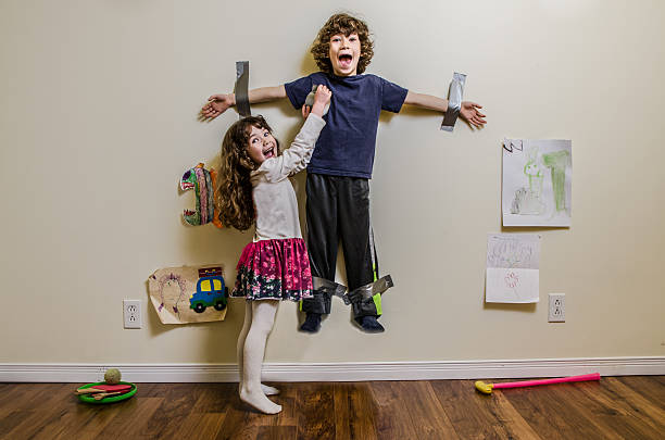 Kid being duct taped on wall by his sister A little girl hung her brother on the wall using duct tape adhesive tape photos stock pictures, royalty-free photos & images