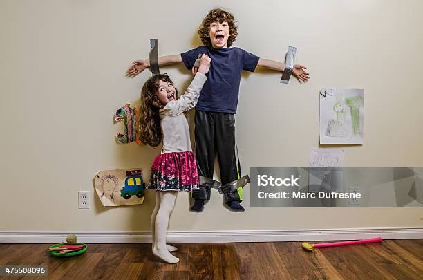 Kid Being Duct Taped On Wall By His Sister Stock Photo - Download Image Now - Child, Humor, Chaos