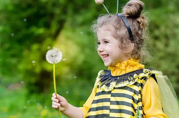 Photo of beautiful girl in a suit bee at park. Happy child
