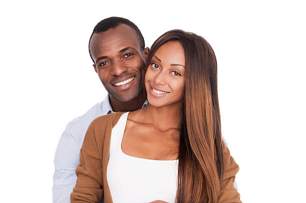 Happy to be together. Beautiful young African couple standing close to each other and smiling at camera while isolated on white attraction studio photography stock pictures, royalty-free photos & images