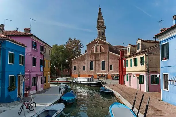 Venice landmark, Burano island canal, colorful houses church and boats, Italy.