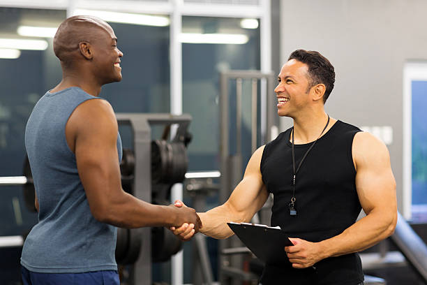 middle aged gym trainer greeting client stock photo