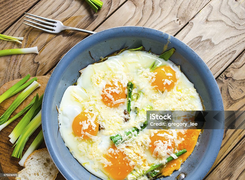 Scrambled eggs Scrambled eggs with leek in pan on wooden table Baguette Stock Photo