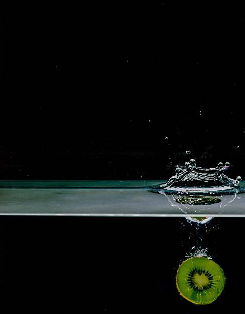 Red apple splashing into water, isolated on black background