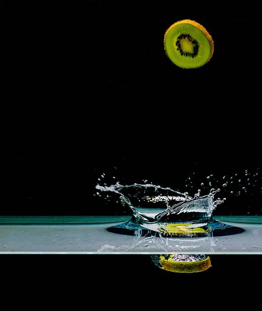 Red apple splashing into water, isolated on black background